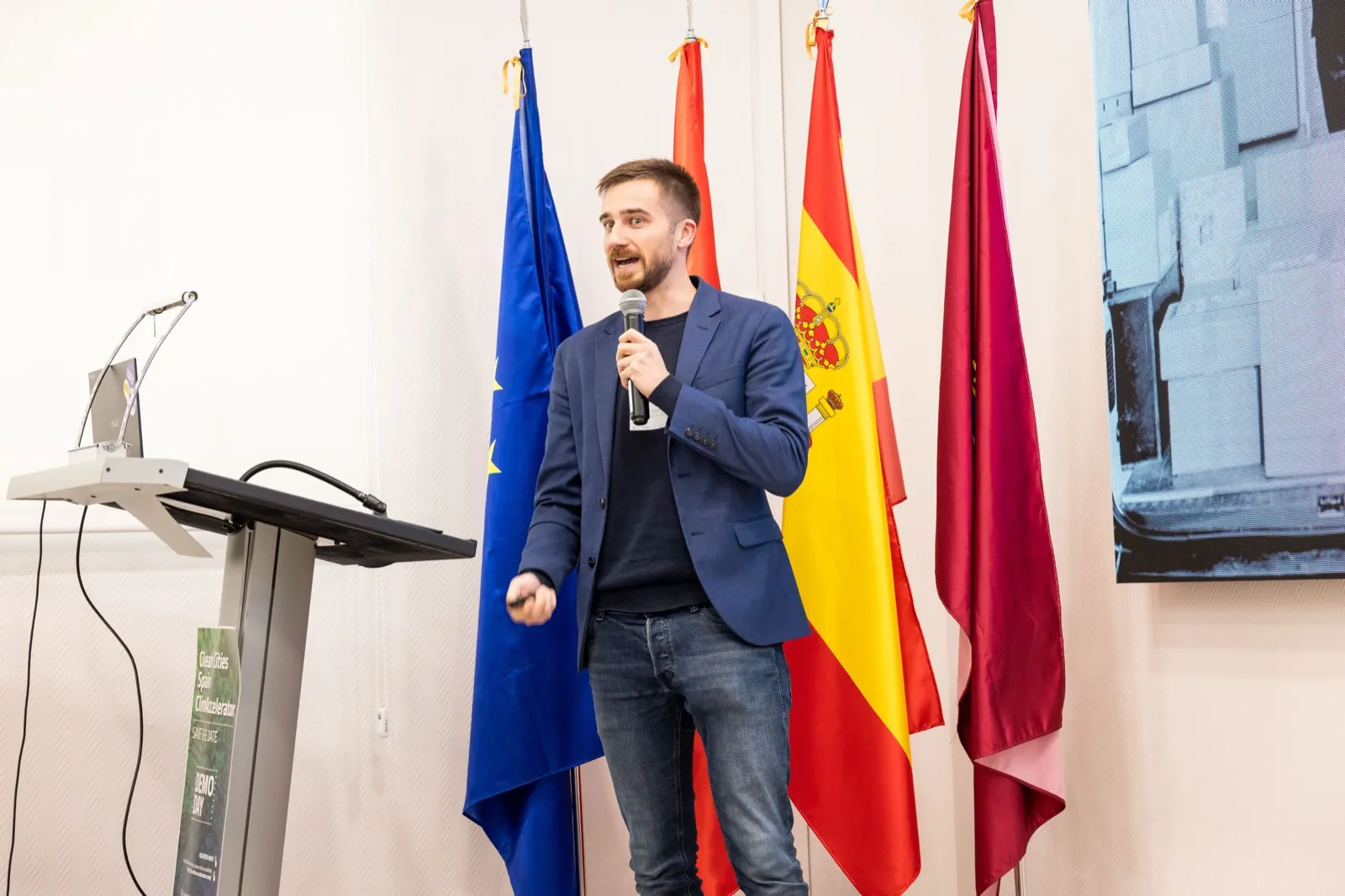 Jakob presentando delante de banderas europeas y españolas en el demo day de Clean Cities ClimAccelerator en Madrid, octubre de 2025.