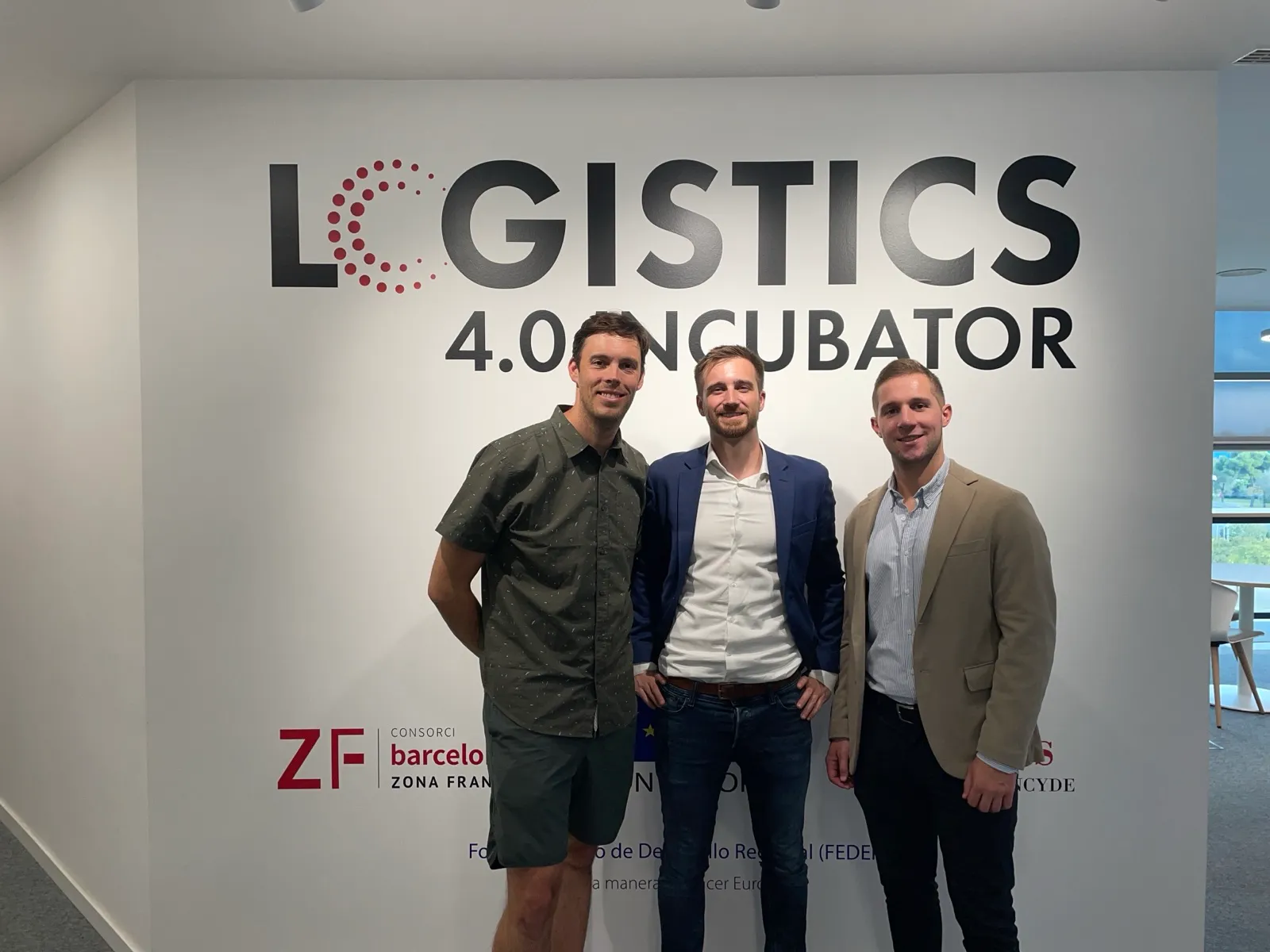 Los tres cofundadores de Grasshopper delante del muro de la Incubadora Logística 4.0 en Barcelona, junio de 2024.